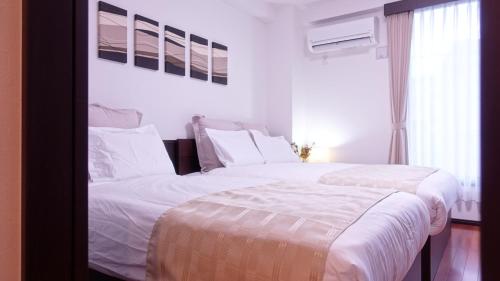 a bedroom with two beds with white sheets and a window at COCORO HOTEL in Kyoto