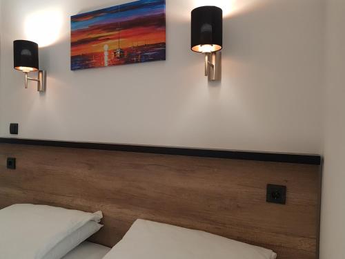 a bedroom with a bed with two lights on the wall at Apartman Simić 2 in Valjevo
