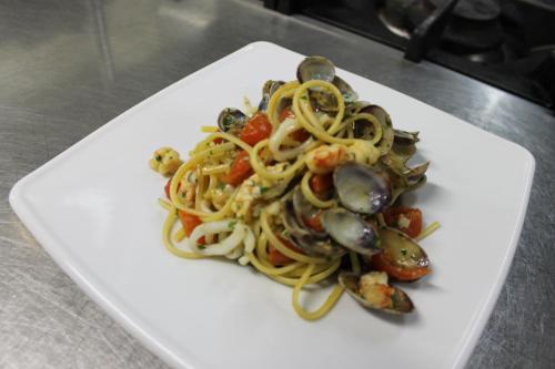 a white plate of pasta with mussels and shrimp at Il Villaggio Di Giuele in Finale Ligure