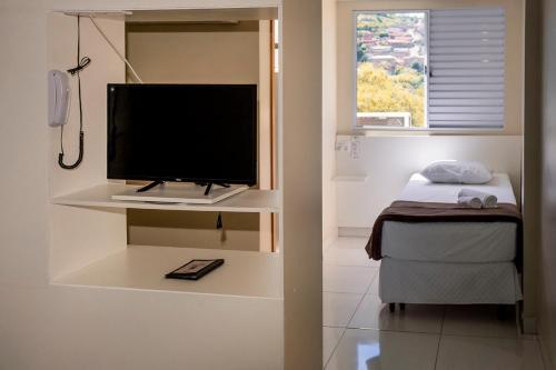 São Gonçalo do Rio AbaixoにあるIron Flat Residence Serviceの壁に薄型テレビが取り付けられたリビングルーム