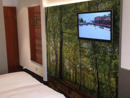 a bedroom with a wall mural of trees with a tv at Hotel am Dom in Fulda