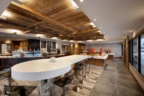 a kitchen with a white counter and a bar with stools at Hôtel Alexane in Samoëns