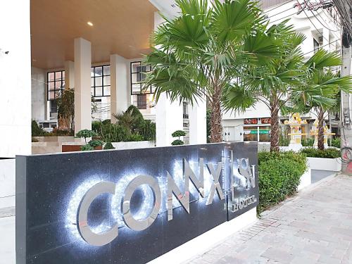 a sign in front of a building with palm trees at SN Connx - SHA Plus in Pattaya Central