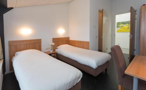 ein Hotelzimmer mit 2 Betten, einem Tisch und einem Schreibtisch in der Unterkunft B&B Restaurant Maria Johanna Hoeve in Noordeloos