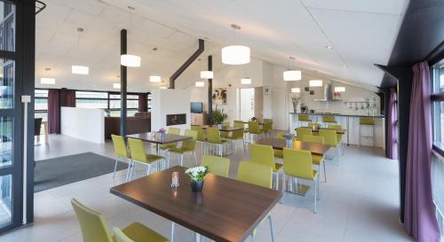 een eetkamer met tafels en gele stoelen bij B&B Restaurant Maria Johanna Hoeve in Noordeloos