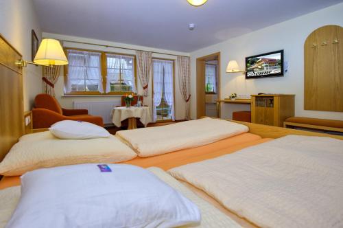 a hotel room with three beds and a television at Gasthaus Sonne in Münstertal