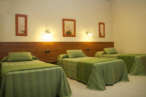 Cette chambre comprend 3 lits avec des draps verts. dans l'établissement Hostal El Catalán, à Madrid