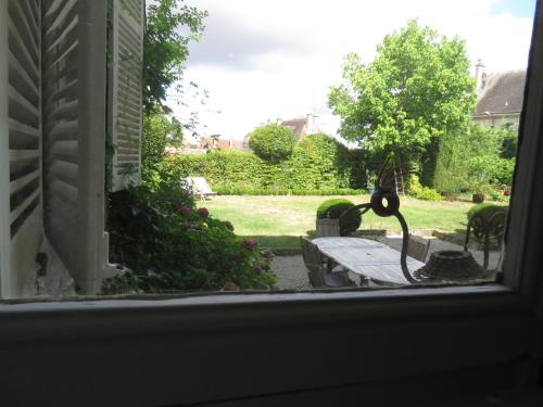 a view from a window of a park with a bench at B&B Le Jardin de Carco in Châtillon-sur-Seine