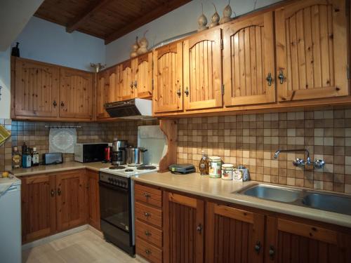 a kitchen with wooden cabinets and a sink at Fey's House waterfront - Φισκάρδο in Fiskardho