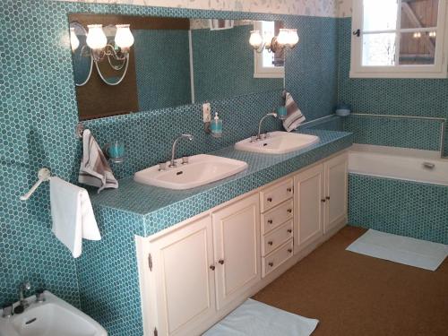 a bathroom with two sinks and a mirror and a tub at Mas du Trezon in Cholet