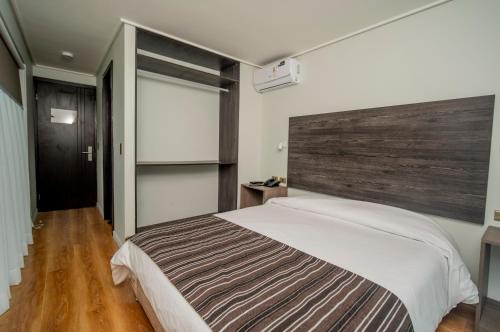 a bedroom with a large bed with a wooden headboard at Hotel Baquedano Boulevard in Iquique