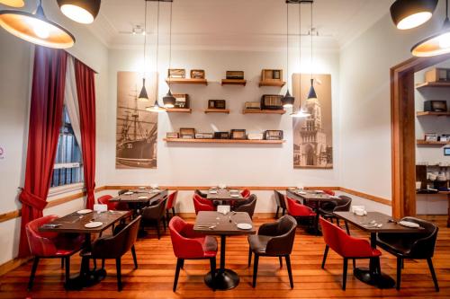 a dining room with tables and red chairs at Hotel Baquedano Boulevard in Iquique