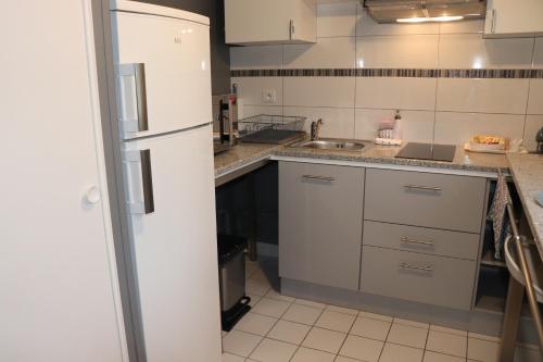 La cuisine est équipée de placards blancs et d'un réfrigérateur blanc. dans l'établissement STUDIO CENTRE VILLE COMPIÈGNE, à Compiègne