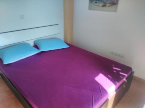 a purple bed with two pillows on top of it at Apartments Bogunovic in Ploče
