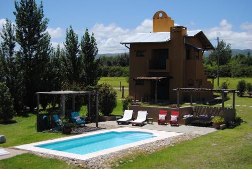 un patio trasero con piscina y una casa en La Cambicha Ranchos en Los Reartes