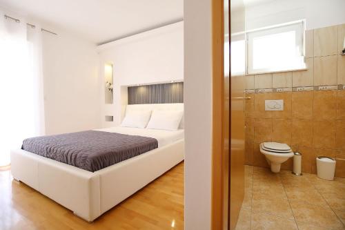 a bedroom with a bed and a bathroom with a toilet at Apartments Tony in Biograd na Moru
