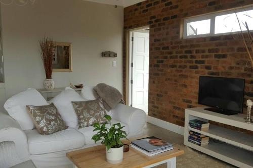 ein Wohnzimmer mit einem weißen Sofa und einer Ziegelwand in der Unterkunft Nova Skye in Johannesburg