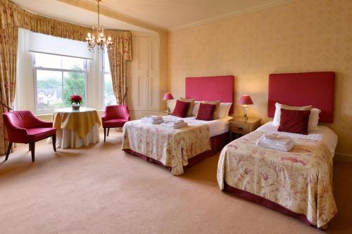 
a hotel room with two beds and two tables at Craigroyston House in Pitlochry
