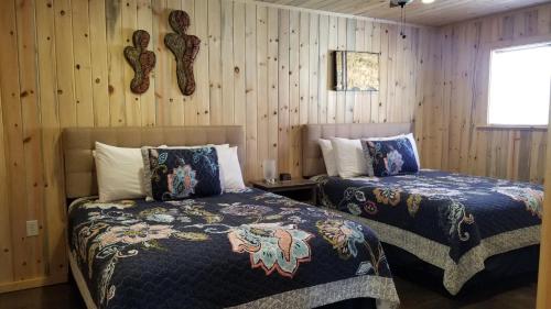 two beds in a room with wood paneled walls at Bluff Gardens in Bluff