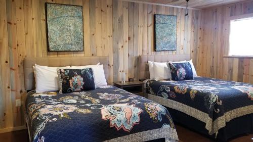 - 2 lits dans une chambre dotée de murs en bois dans l'établissement Bluff Gardens, à Bluff