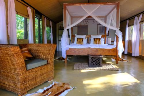 a bedroom with a canopy bed and wicker chairs at DOMUS - Private Bush Camp in Lusaka