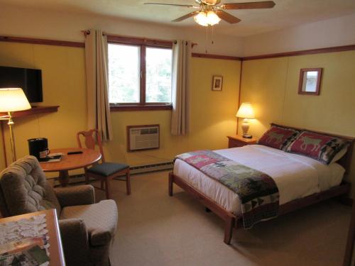 a bedroom with a bed and a table and a chair at Carlson's Lodge in Twin Mountain