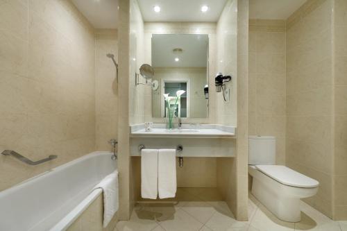 a bathroom with a tub and a sink and a toilet at Exe Gran Hotel Solucar in Sanlúcar la Mayor