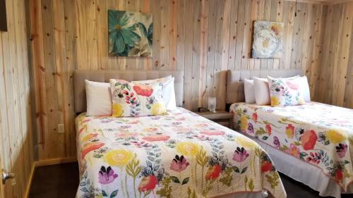two beds in a room with wooden walls at Bluff Gardens in Bluff