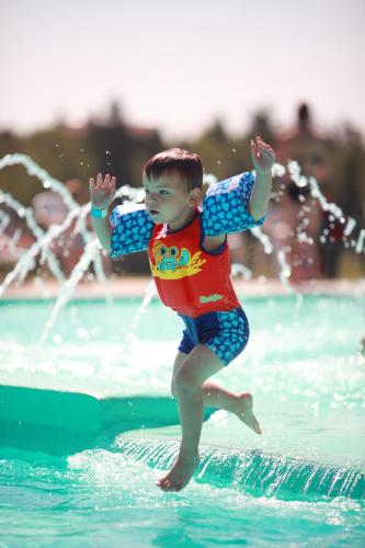 a young boy jumping on a wave in the water at Centre de Villégiature Dam-en-Terre in Alma