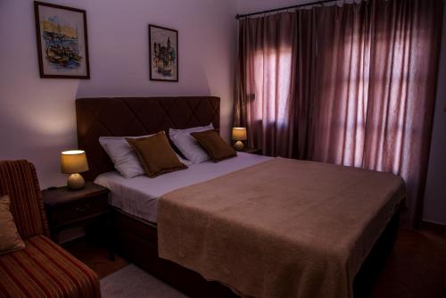 a bedroom with a large bed and a chair at Apartments Klakor PS in Tivat