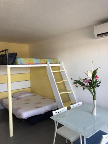 Cette petite chambre comprend des lits superposés et une table. dans l'établissement Studio 21m2 Port-Camargues, le Grau du Roi, au Grau-du-Roi