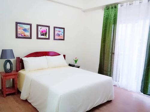 a bedroom with a white bed and a window at Amani Grand Residence near Mactan Cebu Intl Airport in Mactan