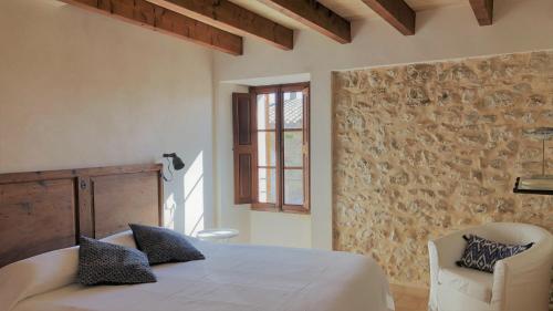 a bedroom with a white bed and a chair at Vista de la Vila - Turismo de interior. in Llubí