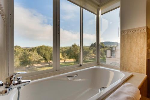 a bath tub in a bathroom with a large window at Arcos Gardens Sol Rent Golf in Arcos de la Frontera