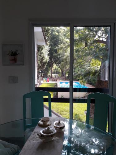 un tavolo di vetro con due sedie verdi e una finestra di La Marea B&B a Tigre
