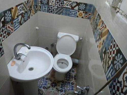 La salle de bains est pourvue de toilettes blanches et d'un lavabo. dans l'établissement Flower Roomsللرجال فقط, à Alexandrie