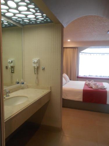 a bathroom with a bed and a sink and a mirror at Hotel Puente Real in Puebla