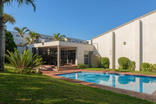 a house with a swimming pool in front of a building at Sands Beach Breaks Umdloti Beach View in Umdloti
