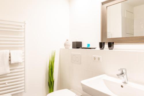 a white bathroom with a sink and a mirror at Intermar Hotel & Apartments in Glücksburg