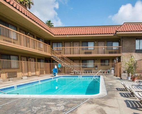 a building with a swimming pool in front of a building at Palm Inn Hotel near Tyler Mall Riverside in Riverside