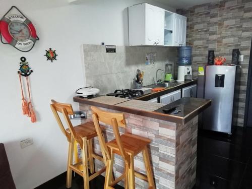 聖安德烈斯的住宿－Posada Leonor，厨房配有带椅子的柜台和冰箱。