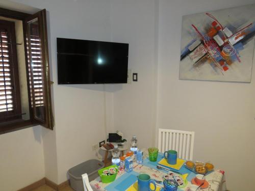 a room with a table with a tv on the wall at Domoruja B&B in Sassari
