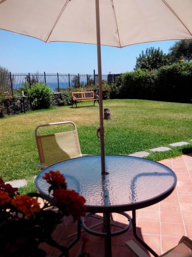 a glass table with an umbrella and a chair at Case Vacanze Residence Trinacria in Acireale