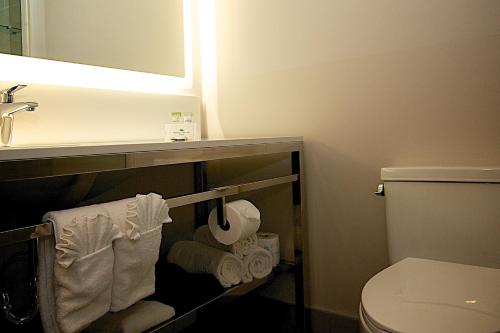 a bathroom with a sink and a toilet and towels at Coast Nisku Inn & Conference Centre in Nisku