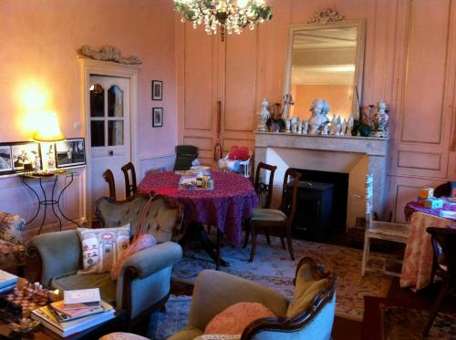 een woonkamer met een tafel en een open haard bij Maison Marthe B & B in Saint-Sauveur-en-Puisaye