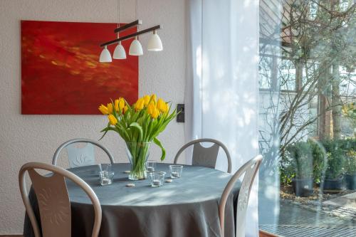 einen Esstisch mit gelben Blumen in einer Vase in der Unterkunft FeWo Litzendorf in Litzendorf