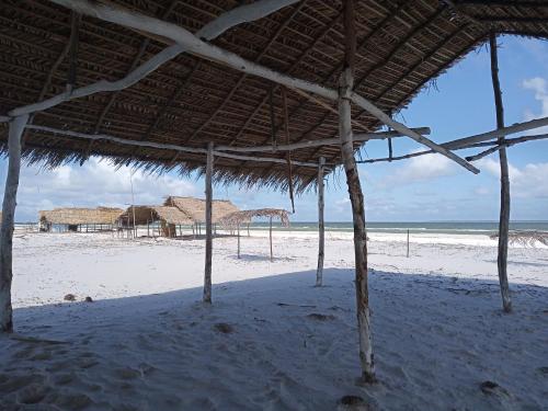 a large straw hut on a beach with the ocean at La Luna Fortalezinha in Algodoal