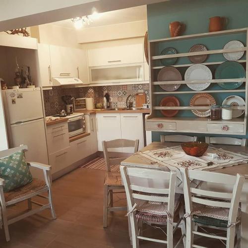 une cuisine avec une table, des chaises et des assiettes sur les étagères dans l'établissement Tsiboulas Cretan Cottage, à Kritsa