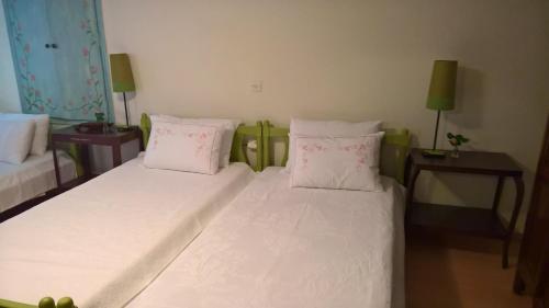 a bedroom with a bed with white sheets and pink pillows at Spitaki Spata Airport Studio in Spáta