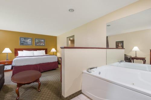 a hotel room with a bed and a bath tub at Days Inn by Wyndham Norton in Norton
